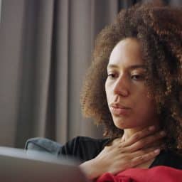 Woman with laryngitis feeling her throat.