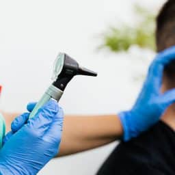 Man receiving an ear exam for ear pain.