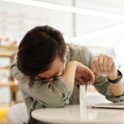 Man sneezing into his arm while out at a cafe.