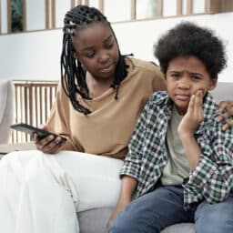 Mom and kid sitting on a couch, kid experiencing tooth pain