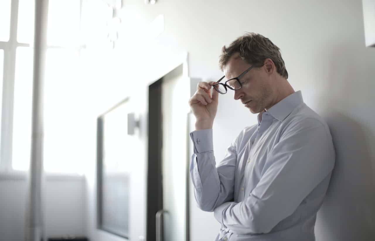 Young man standing against a wall looking stressed.