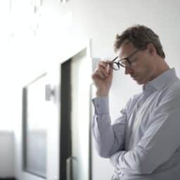 Young man standing against a wall looking stressed.