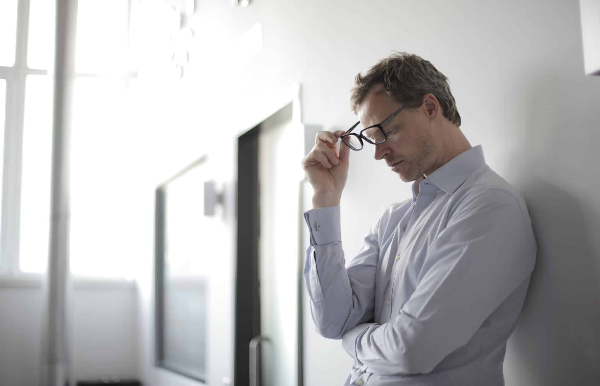 Young man standing against a wall looking stressed.