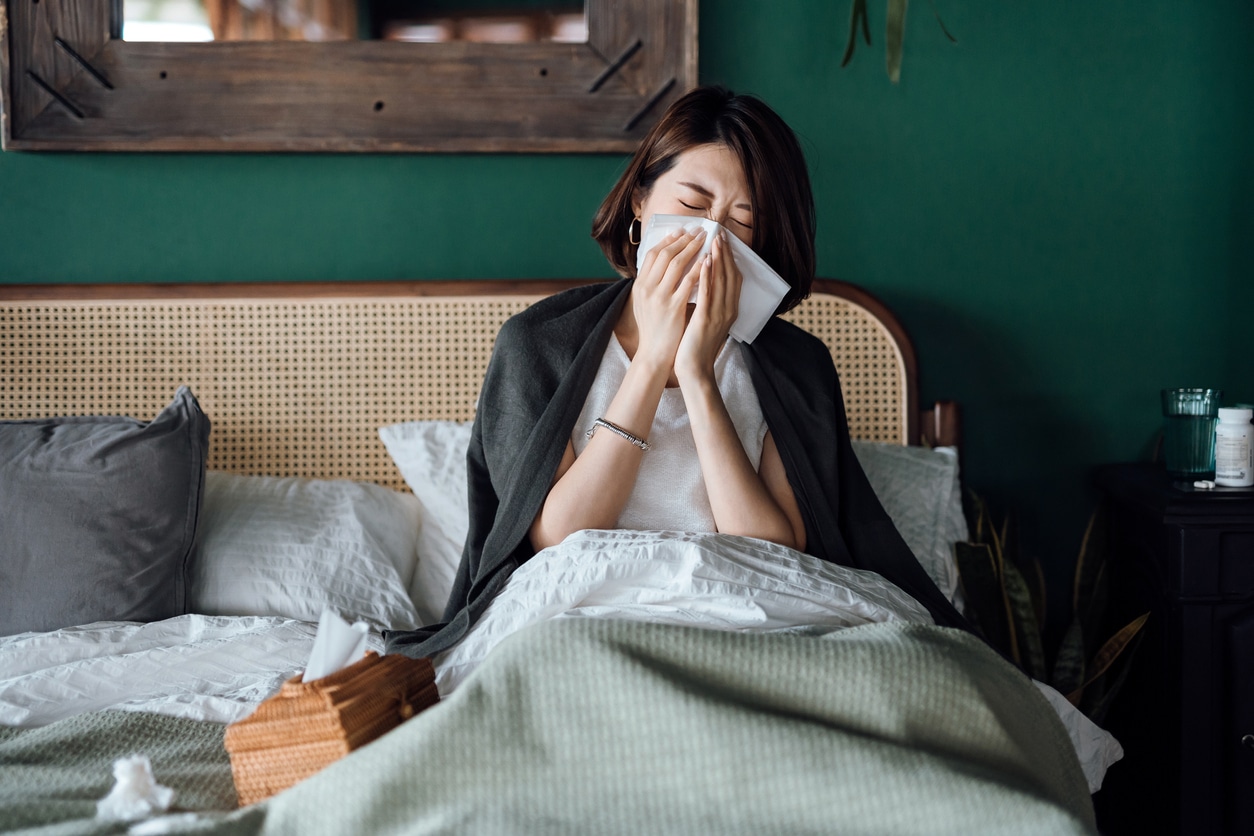 Woman blowing her nose in bed.
