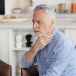Senior man feeling his throat.