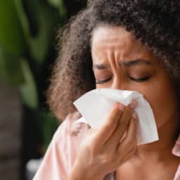 Woman sneezes into tissue
