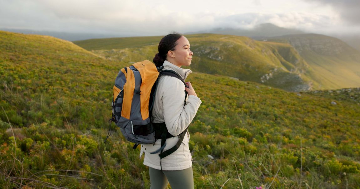 woman hiking through green hills