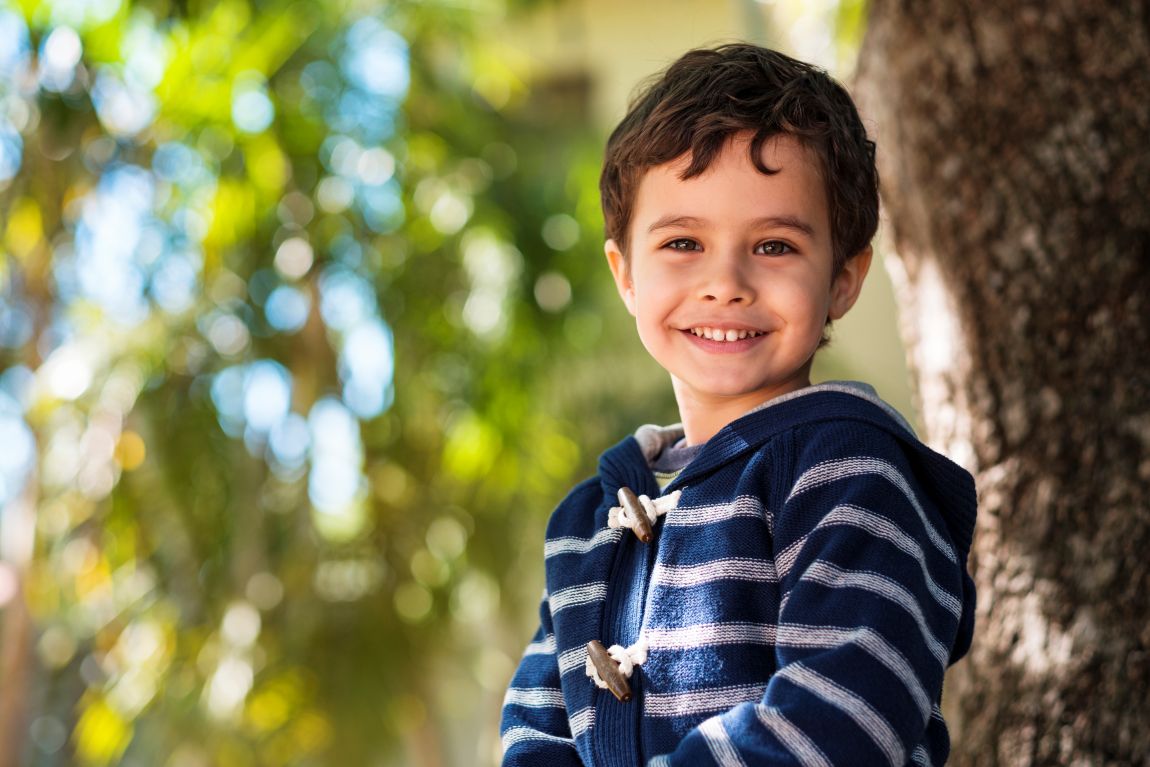little boy smiling by tree
