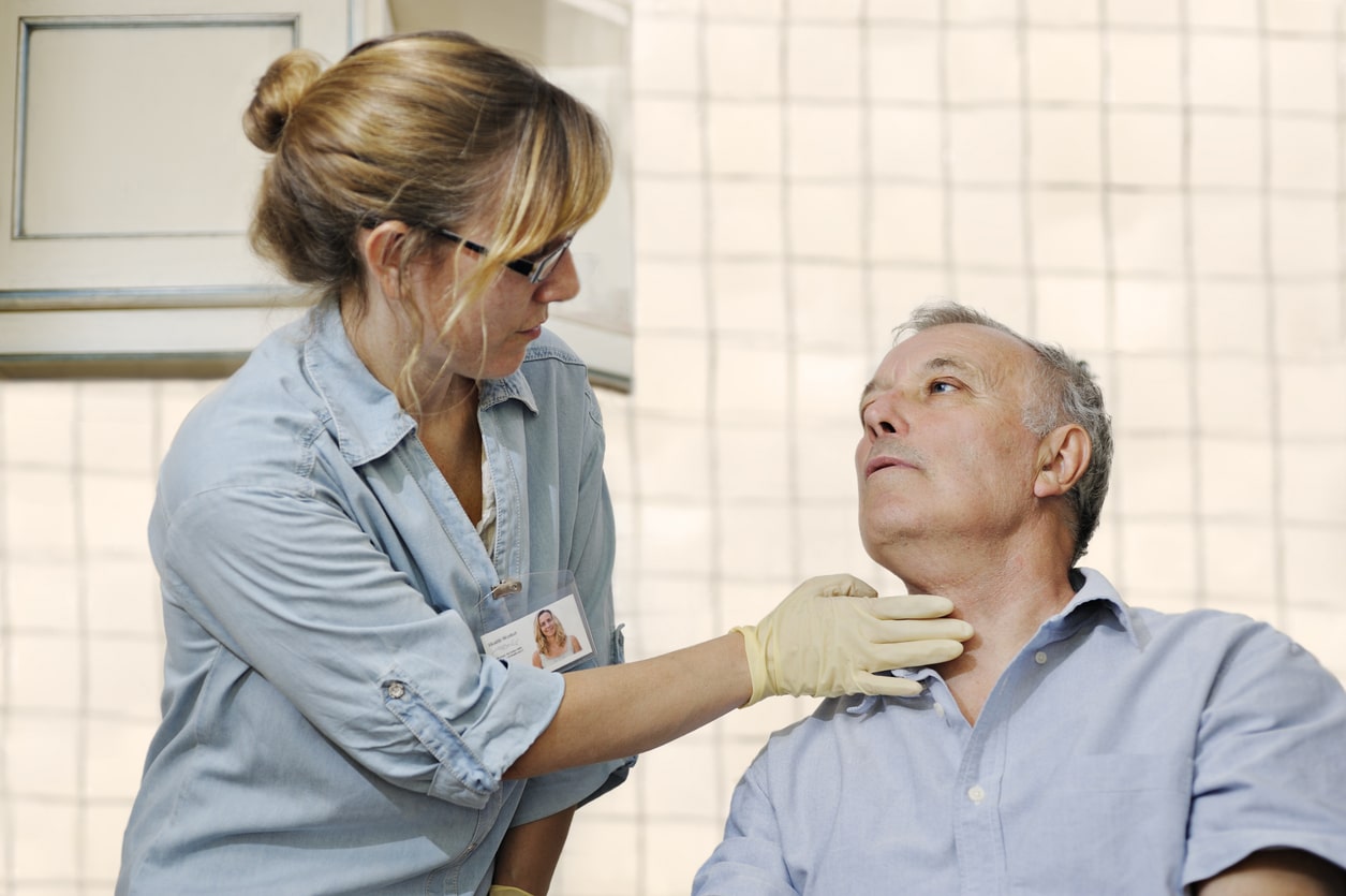 Healthcare worker checking man's throat.