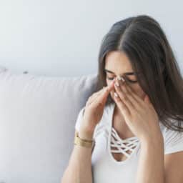 Woman holding her nose and head because sinus pain