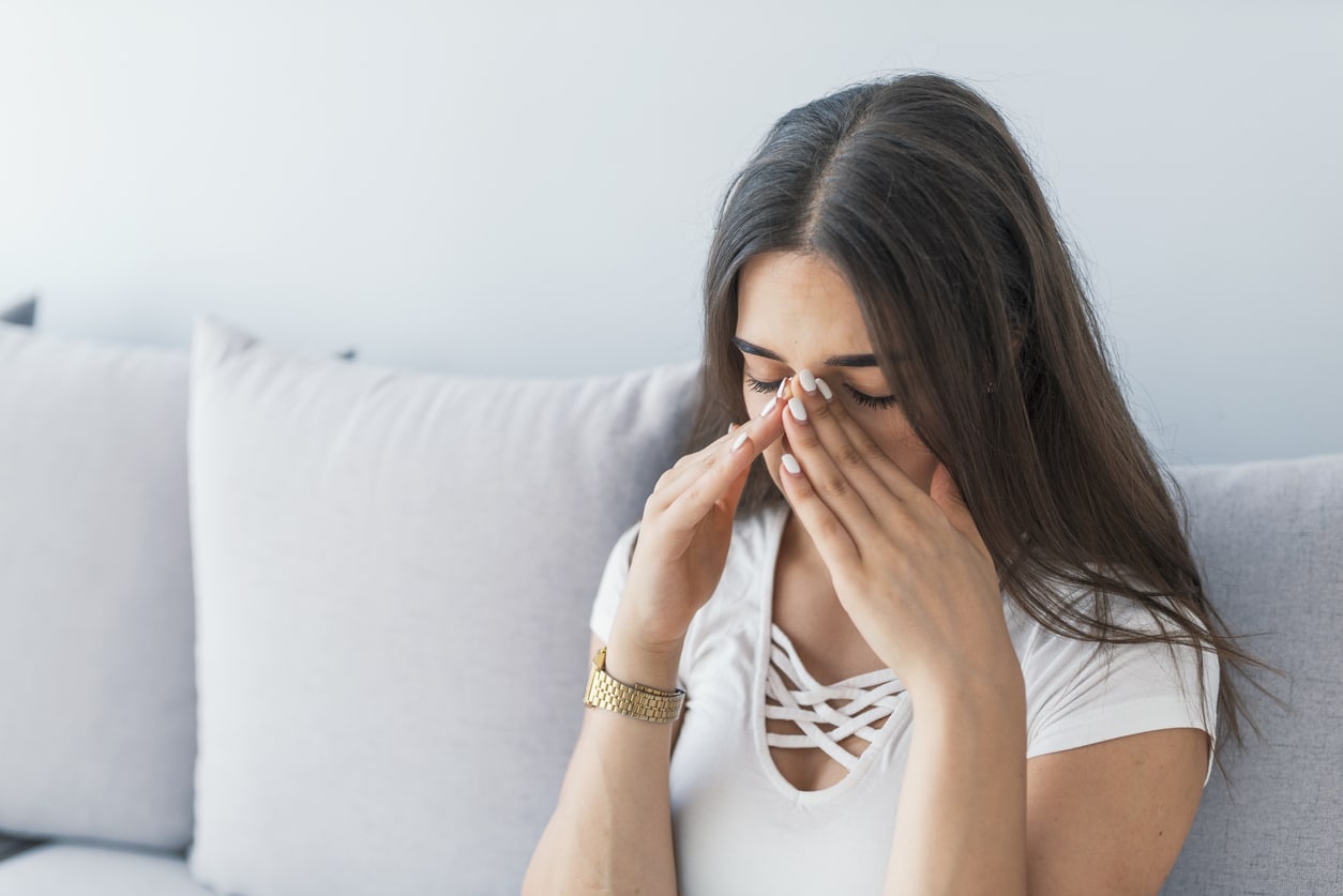 Woman holding her nose and head because sinus pain.