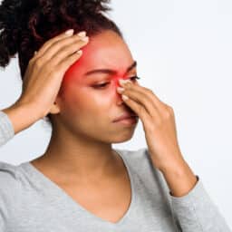 Woman with sinusitis holding her red nose and forehead