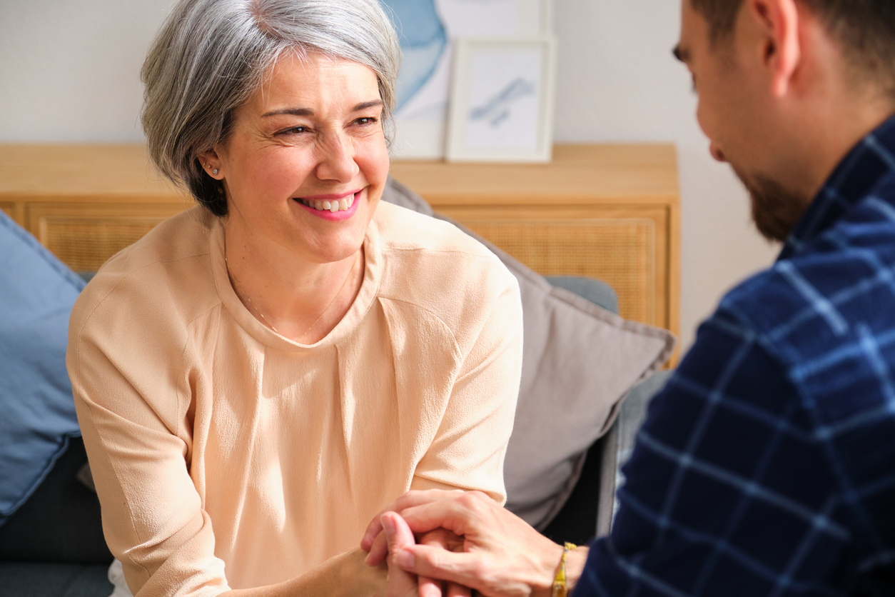 A man is holding a woman's hands and talking to her.